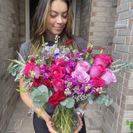 Woman holding a large bouquet of pink and purple roses in a glass vase