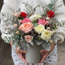 Mixed pink, peach, white, and red roses in a gray vase