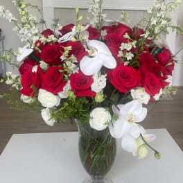 Red roses and white orchids arranged in a clear glass vase
