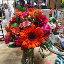 Bright mixed bouquet in a clear glass vase with orange and pink flowers