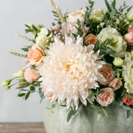 Bouquet of pale peach and white flowers in a round vase