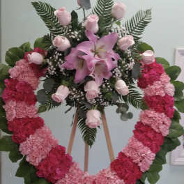 Heart-shaped floral wreath with pink roses and lilies on an easel