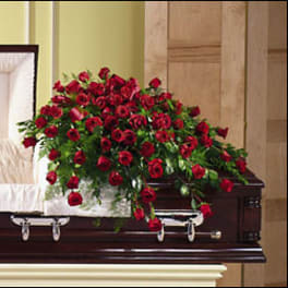 Red rose casket spray on a dark wood casket