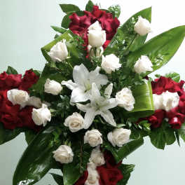 Cross-shaped floral arrangement of red and white roses with lilies