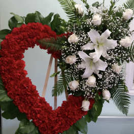Heart-shaped red floral wreath beside a white lily and rose spray