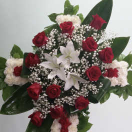 Standing floral spray with red roses, white lilies, and a red-and-white carnation cross