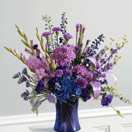 Purple and blue floral arrangement in a cobalt vase