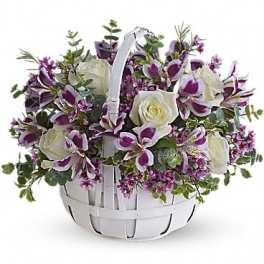 White basket arrangement with white roses and purple orchids
