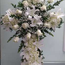 Large white floral cross arrangement with lilies and roses