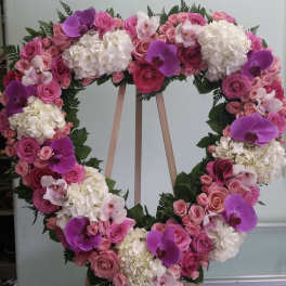 Heart-shaped floral wreath with pink roses, white hydrangeas, and purple orchids