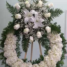 White floral standing wreath with lilies, roses, and hydrangeas