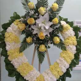 Heart-shaped floral wreath with yellow roses and white lilies on an easel