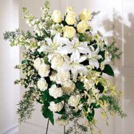 Standing spray of white lilies and pale yellow roses on a metal easel
