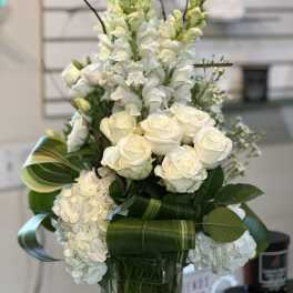 White roses and snapdragons arranged in a glass vase