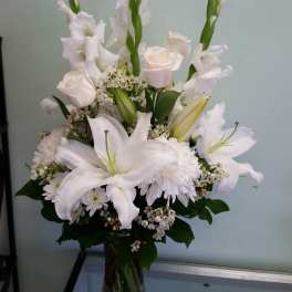 White lilies and roses arranged in a clear glass vase