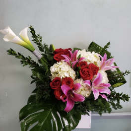 Bouquet of red roses, pink lilies, and white calla lilies in a white vase