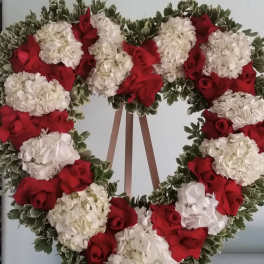 Heart-shaped wreath of red roses and white hydrangeas on an easel