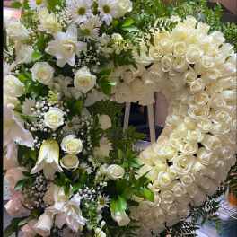 Large white floral wreath with roses and daisies on an easel