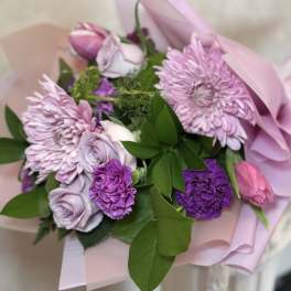 Pink and purple bouquet with chrysanthemums, roses, and carnations wrapped in pastel paper