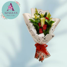 Bouquet of red roses and white lilies wrapped in printed paper with a red ribbon