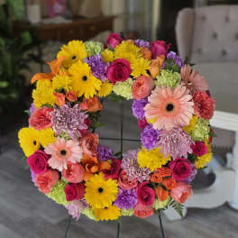 Colorful floral wreath on a metal stand with roses and daisies