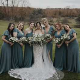 Bride and bridesmaids holding white bouquets outdoors
