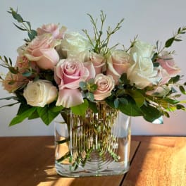 Pink and white roses arranged in a clear glass vase