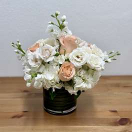 White and peach roses arranged in a black vase