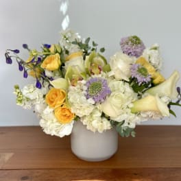 Mixed bouquet of white, yellow, and lavender flowers in a white vase