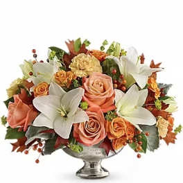 Autumn floral arrangement with roses, lilies, and carnations in a silver vase