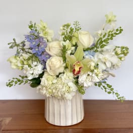 Mixed bouquet in a cream ribbed vase with white, pale pink, and blue flowers