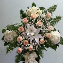 Standing floral cross with white blooms, peach roses, and fern fronds