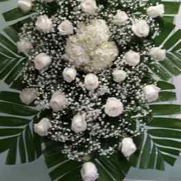 White rose and hydrangea funeral spray with palm leaves