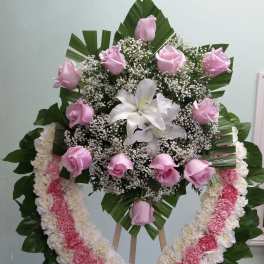 Standing floral wreath with pink roses, white lilies, and a pink-and-white garland