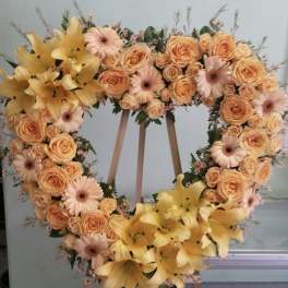 Heart-shaped floral wreath with peach roses, pink daisies, and yellow lilies