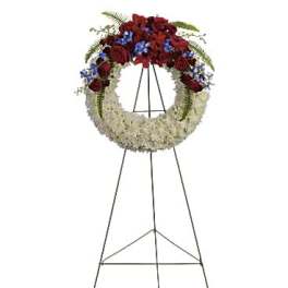 Standing funeral wreath with red roses, white flowers, and blue accents