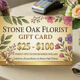 Stone Oak Florist gift card on a table between two peach rose and hydrangea arrangements in glass vases
