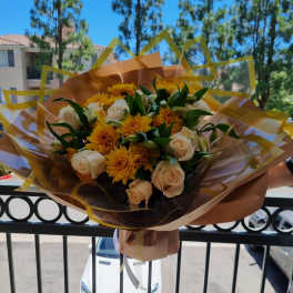 Bouquet of cream roses and yellow chrysanthemums wrapped in brown paper
