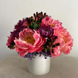 Pink and purple flowers arranged in a white vase