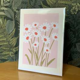 Framed print of white daisies with red centers on a pink background