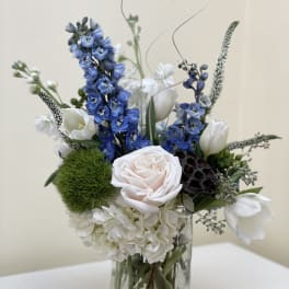 Blue and white floral arrangement in a clear glass vase