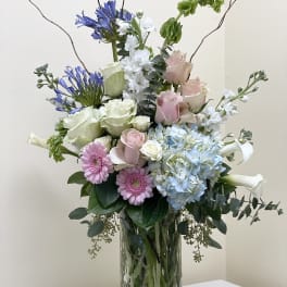 Mixed bouquet of pastel flowers in a clear glass vase