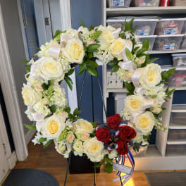 Heart-shaped floral wreath with white and red roses on a stand