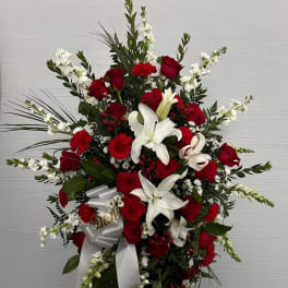 Standing floral spray with red roses and white lilies on a white ribboned easel