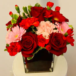 Red roses and pink daisies in a square glass vase