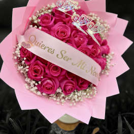 Bouquet of bright pink roses with baby's breath, pink wrapping, and a ribbon with Spanish proposal text