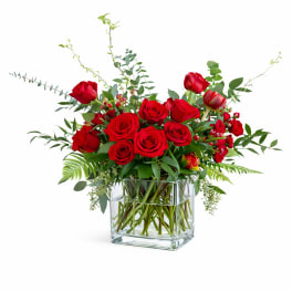 Red roses arranged in a clear square glass vase