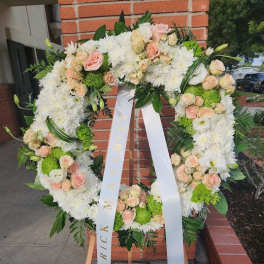 Standing wreath of white mums and peach roses with ribbon on wooden easel