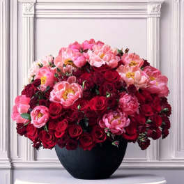 Large bouquet of pink and red flowers in a black vase