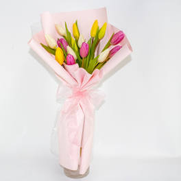Pink, yellow, and white tulips wrapped in pale pink paper